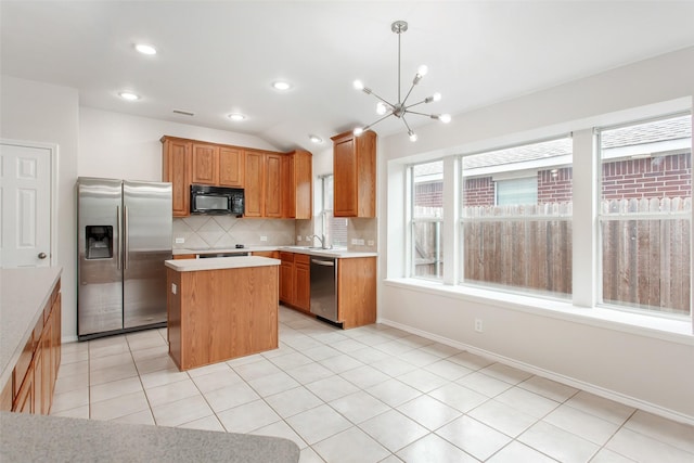 kitchen with stainless steel appliances, vaulted ceiling, a notable chandelier, a kitchen island, and hanging light fixtures