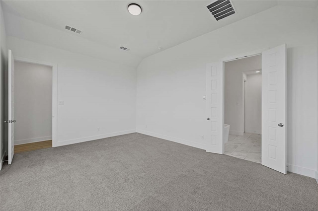 spare room featuring light colored carpet and vaulted ceiling