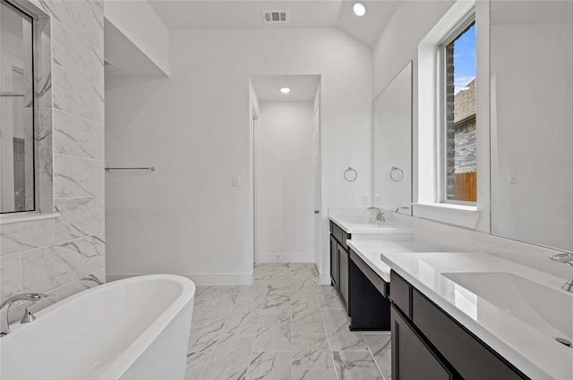 bathroom with tile patterned flooring, a washtub, lofted ceiling, and double sink vanity