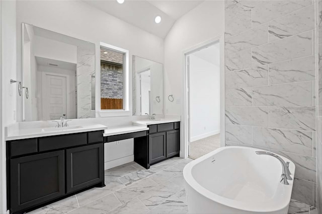 bathroom featuring a tub to relax in, tile patterned floors, lofted ceiling, and double vanity