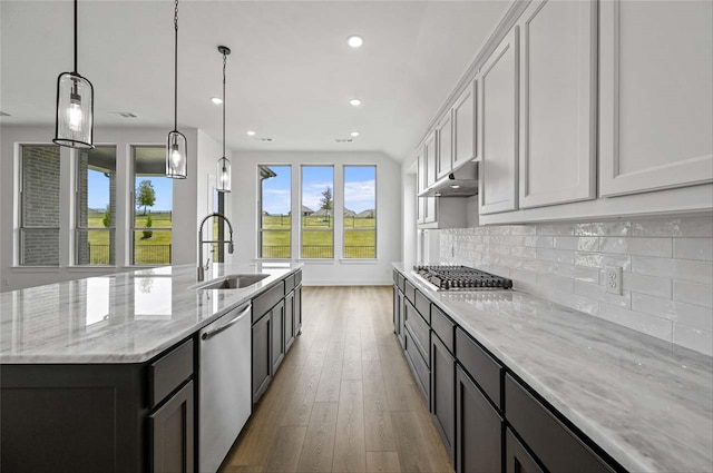 kitchen featuring backsplash, a kitchen island with sink, stainless steel appliances, light hardwood / wood-style floors, and sink