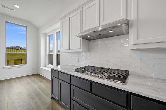 kitchen featuring white cabinets, backsplash, light stone counters, light hardwood / wood-style floors, and stainless steel gas cooktop