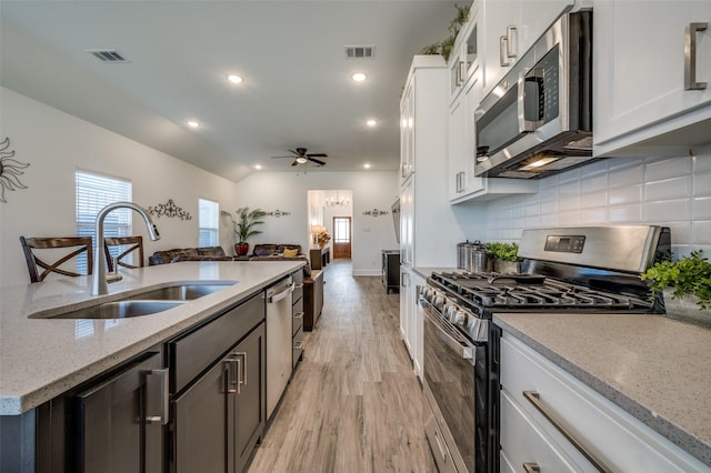 kitchen with stainless steel appliances, visible vents, a sink, and backsplash