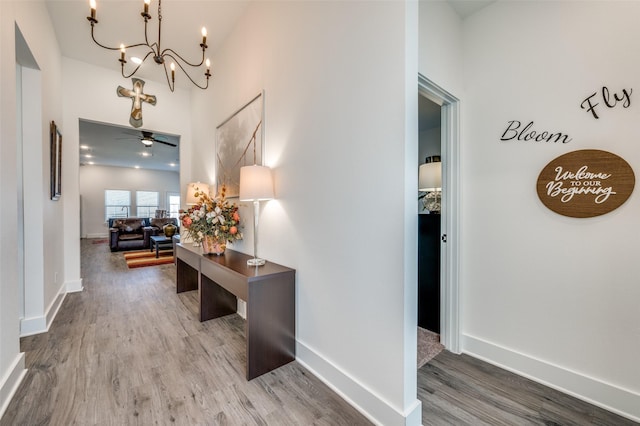 hallway with a notable chandelier, baseboards, and wood finished floors