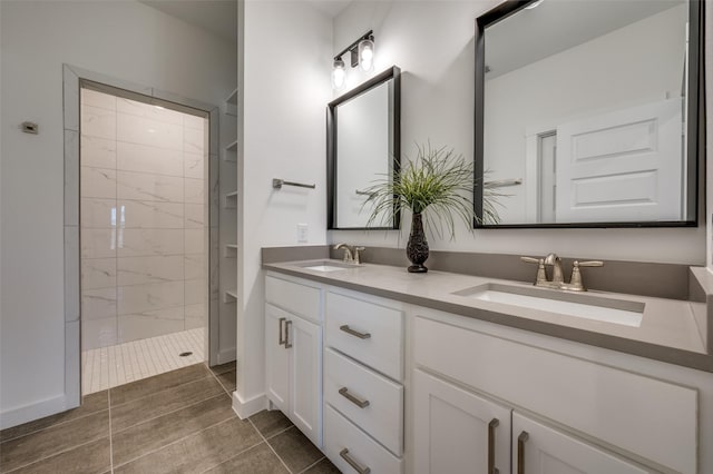 bathroom featuring tiled shower, a sink, and double vanity