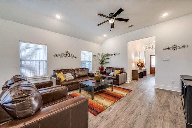 living room with visible vents, baseboards, lofted ceiling, light wood-type flooring, and ceiling fan with notable chandelier