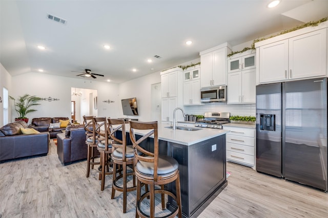 kitchen featuring a breakfast bar, light wood finished floors, visible vents, appliances with stainless steel finishes, and a sink