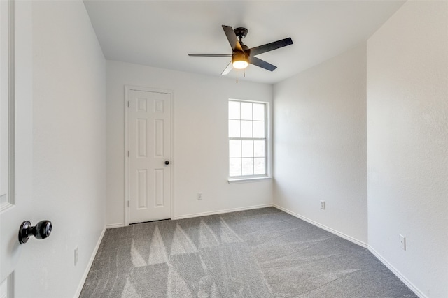 unfurnished room featuring ceiling fan and dark colored carpet