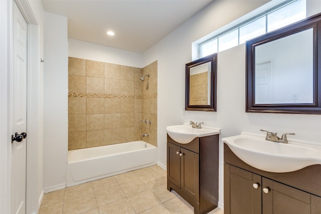 bathroom with vanity with extensive cabinet space, double sink, tile floors, and tiled shower / bath