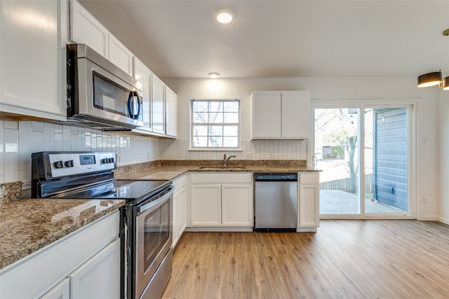 kitchen featuring white cabinets, stone counters, appliances with stainless steel finishes, and light wood-type flooring