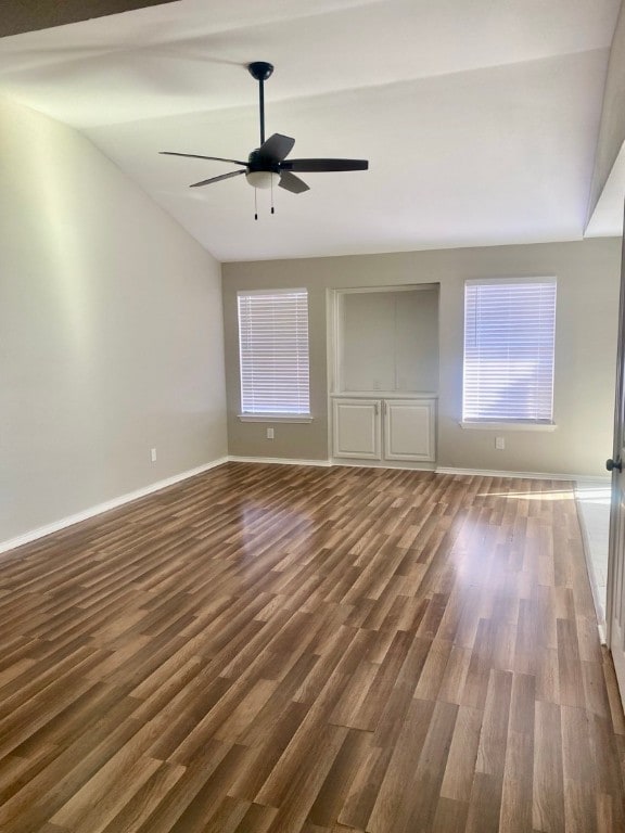 empty room featuring ceiling fan, lofted ceiling, and dark wood-type flooring