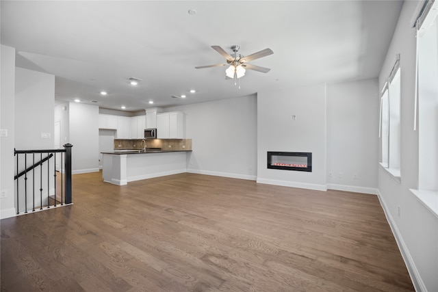 unfurnished living room with ceiling fan, sink, and light wood-type flooring