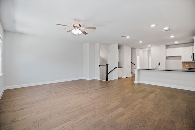 unfurnished living room with light wood-type flooring, ceiling fan, and sink