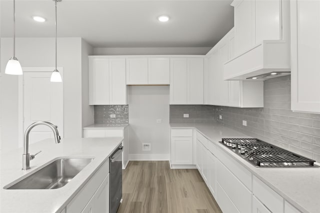 kitchen featuring appliances with stainless steel finishes, decorative light fixtures, sink, white cabinets, and hardwood / wood-style flooring