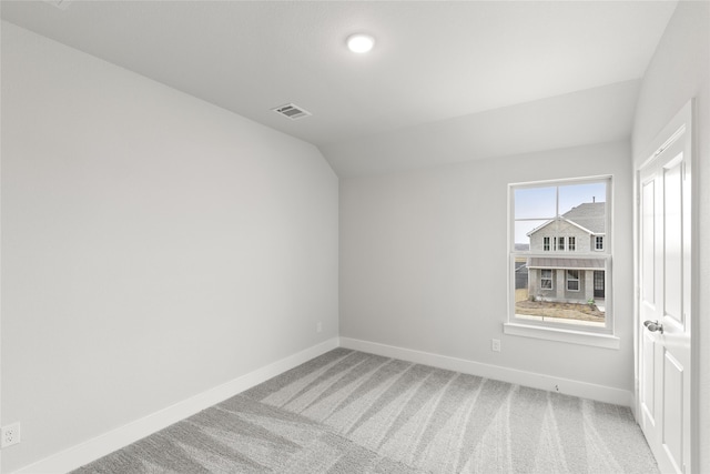 unfurnished room featuring lofted ceiling and carpet