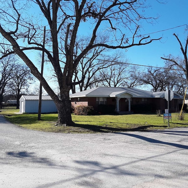 ranch-style home featuring a front yard and an outbuilding