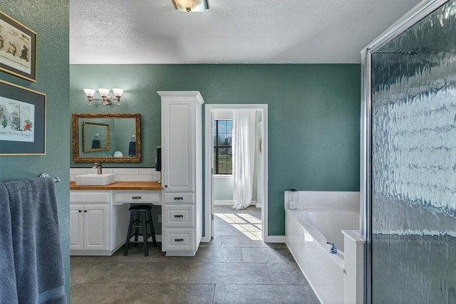 bathroom with a textured ceiling, vanity, and separate shower and tub