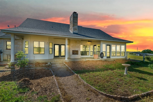 back house at dusk with a patio area and a lawn