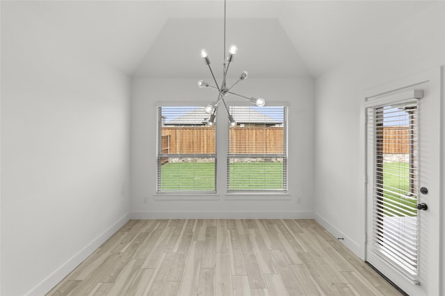 unfurnished room featuring a wealth of natural light, an inviting chandelier, and light hardwood / wood-style floors