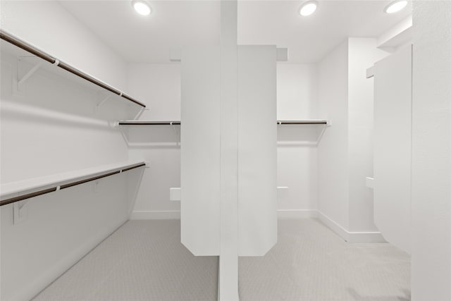 walk in closet with light carpet