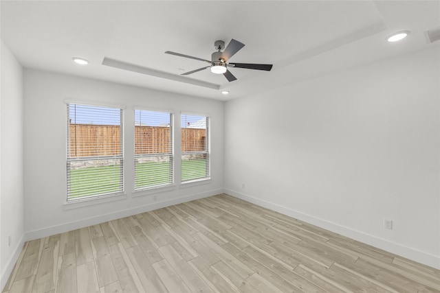 unfurnished room featuring light hardwood / wood-style flooring, a raised ceiling, and ceiling fan