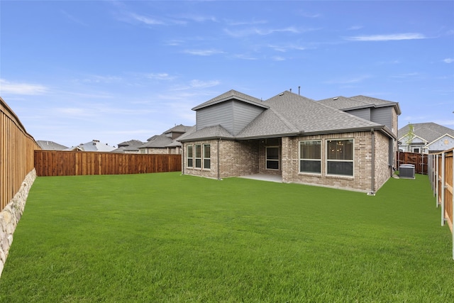 rear view of house with a patio, a lawn, and central AC