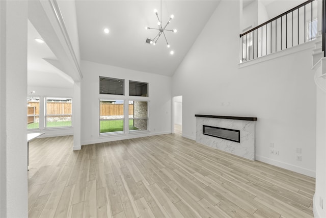 unfurnished living room featuring a healthy amount of sunlight, high vaulted ceiling, and light wood-type flooring