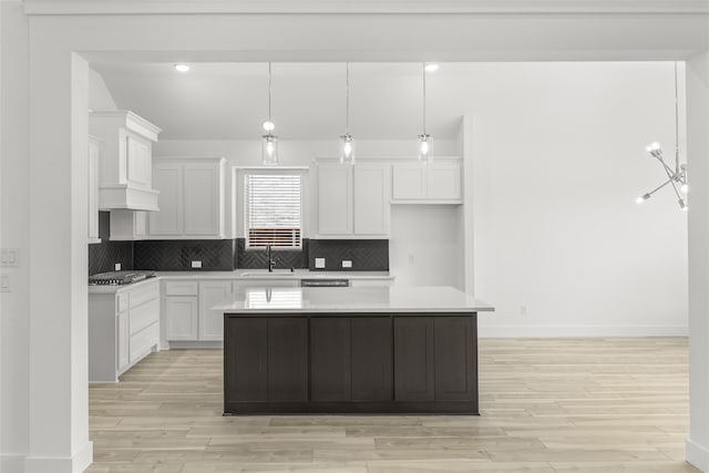 kitchen featuring a center island, pendant lighting, white cabinetry, sink, and tasteful backsplash