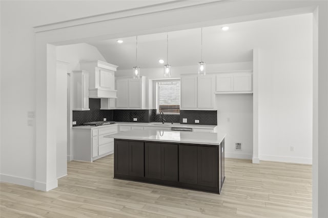 kitchen featuring stainless steel gas stovetop, white cabinets, sink, pendant lighting, and a center island