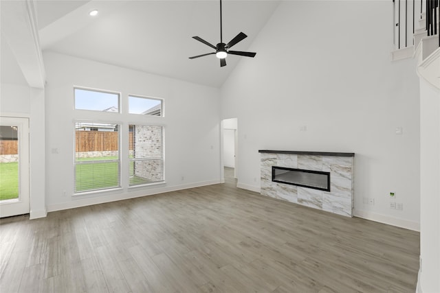 unfurnished living room with high vaulted ceiling, light hardwood / wood-style floors, ceiling fan, and a fireplace