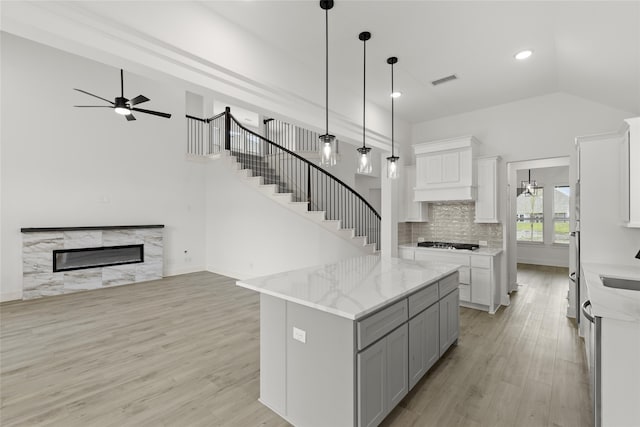 kitchen with light hardwood / wood-style floors, ceiling fan, white cabinets, and a fireplace