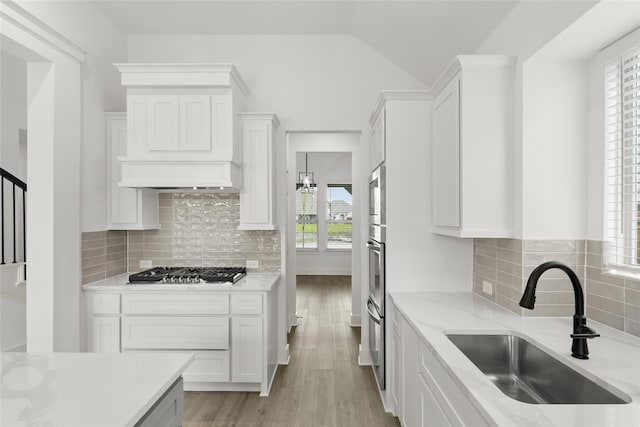 kitchen featuring white cabinets, sink, backsplash, stainless steel appliances, and light hardwood / wood-style flooring