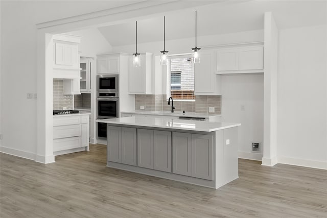 kitchen featuring appliances with stainless steel finishes, a center island, tasteful backsplash, and light hardwood / wood-style floors