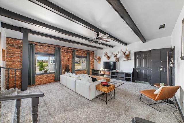 carpeted living room featuring beam ceiling, ceiling fan, and brick wall