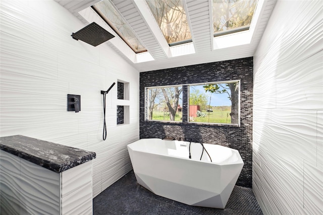 bathroom featuring tile patterned flooring, a washtub, lofted ceiling with skylight, and tile walls