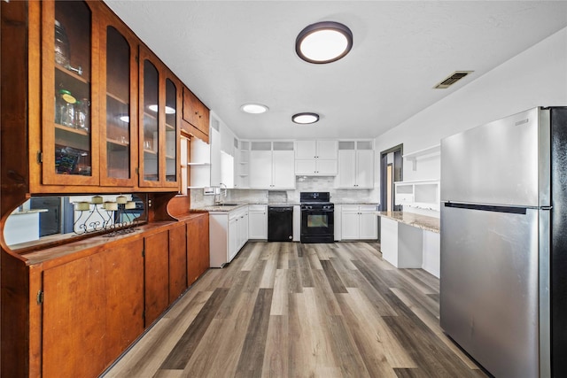 kitchen with black appliances, white cabinets, sink, light wood-type flooring, and tasteful backsplash