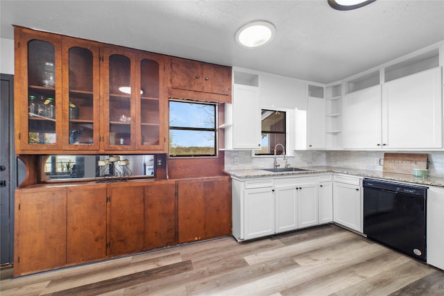 kitchen with black dishwasher, white cabinetry, light stone counters, and sink