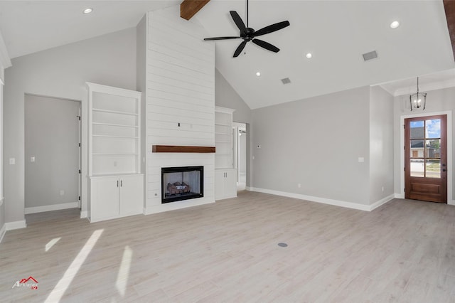 unfurnished living room featuring ceiling fan with notable chandelier, high vaulted ceiling, beamed ceiling, a large fireplace, and light hardwood / wood-style floors