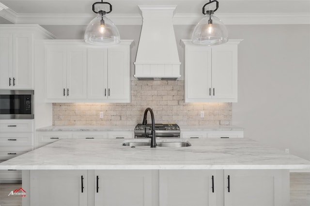 kitchen with stainless steel microwave, decorative light fixtures, white cabinets, custom exhaust hood, and light stone countertops