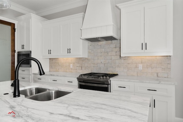 kitchen featuring sink, stainless steel range with gas cooktop, custom range hood, and white cabinets