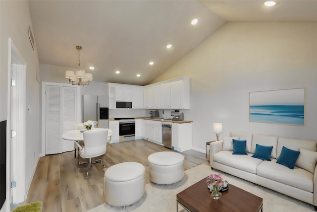 living room with an inviting chandelier, high vaulted ceiling, and light hardwood / wood-style floors