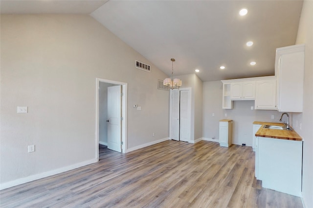 kitchen featuring light hardwood / wood-style flooring, sink, a notable chandelier, and white cabinetry