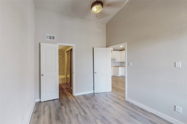 unfurnished bedroom featuring ceiling fan, a high ceiling, and light hardwood / wood-style floors