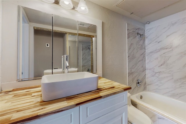 full bathroom featuring toilet, tiled shower / bath combo, and vanity