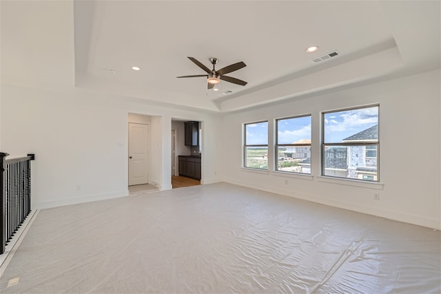 unfurnished living room with ceiling fan and a raised ceiling