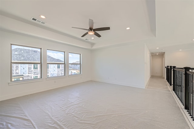 unfurnished room with ceiling fan and a tray ceiling