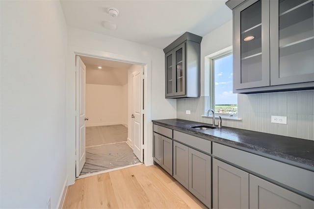 kitchen with tasteful backsplash, light wood-type flooring, sink, and gray cabinets