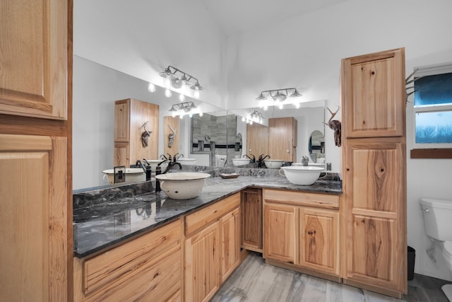 kitchen featuring sink, dark stone counters, and light hardwood / wood-style floors