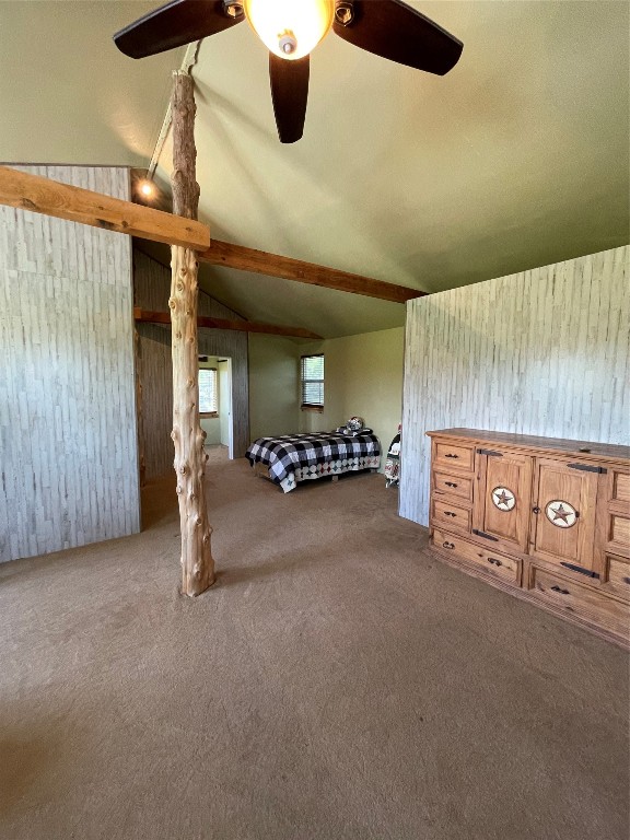 unfurnished bedroom featuring ceiling fan, vaulted ceiling with beams, and carpet flooring