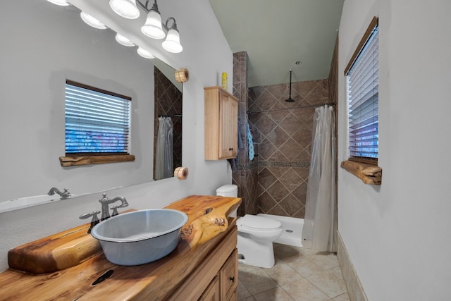 bathroom featuring tile flooring, vanity, toilet, and curtained shower